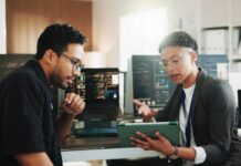 Staging Tables 101, The Safest Way to Integrate Your Website With an ERP Developers reviewing database information on a tablet in an office